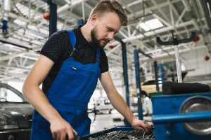 Mężczyzna pracujący w przemyśle motoryzacyjnym, wykorzystujący materiały takie jak PA11 Poliamid w produkcji części samochodowych.