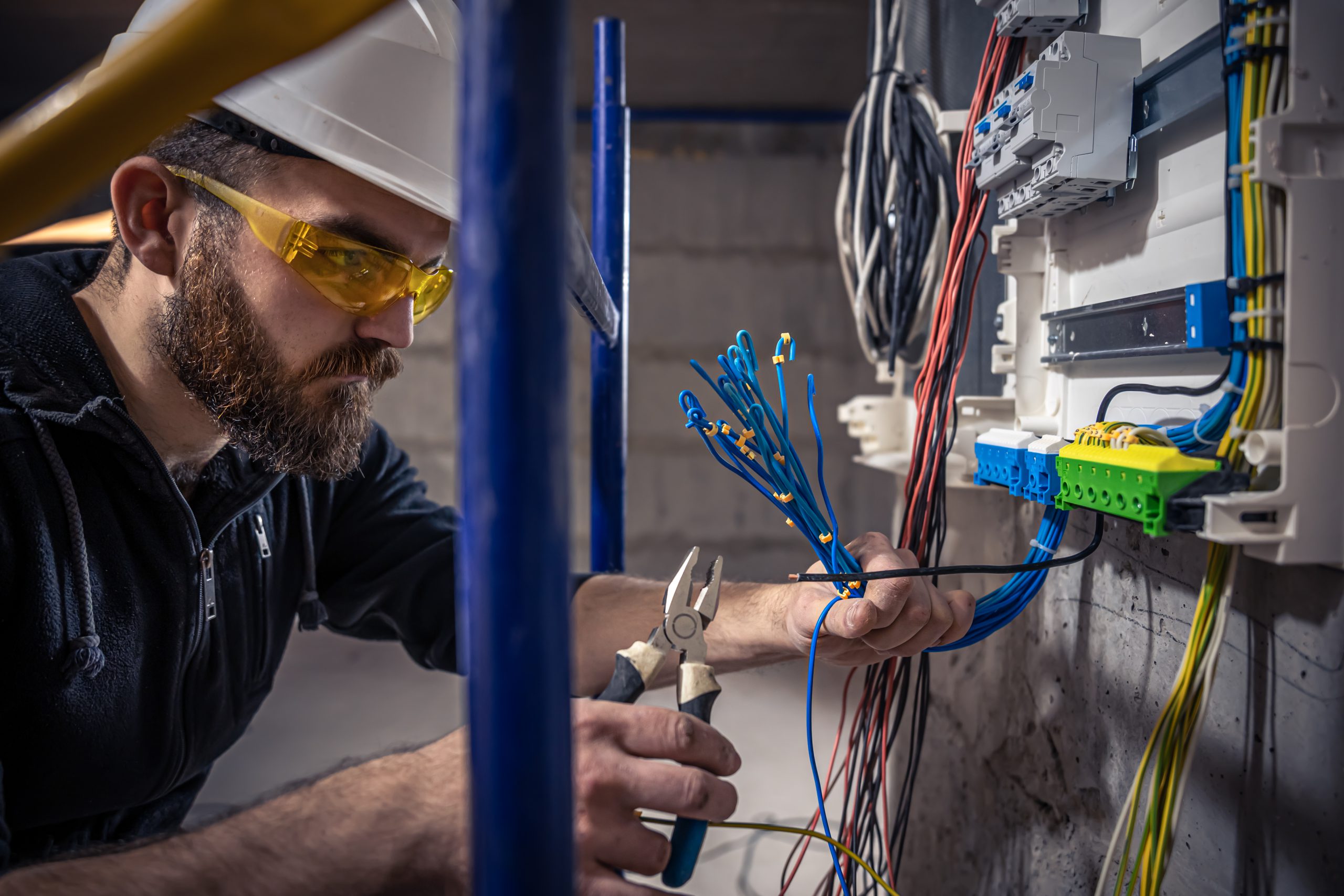 Mężczyzna wykonujący naprawę przewodów elektrycznych w ramach serwisu instalacji niskoprądowych.