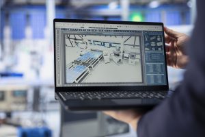 Inżynier z firmy drogowej w Małopolsce analizujący projekt 3D inwestycji infrastrukturalnej na ekranie laptopa w nowoczesnym biurze.
