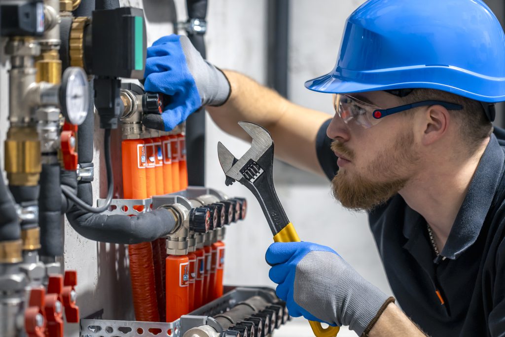 Specjalista podczas pracy wykonujący serwis instalacji przeciwpożarowych przy zaworach i elementach armatury.