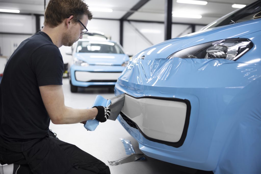 Specjalista nakłada powłoki fluoropolimerowe na zderzak samochodu w warsztacie